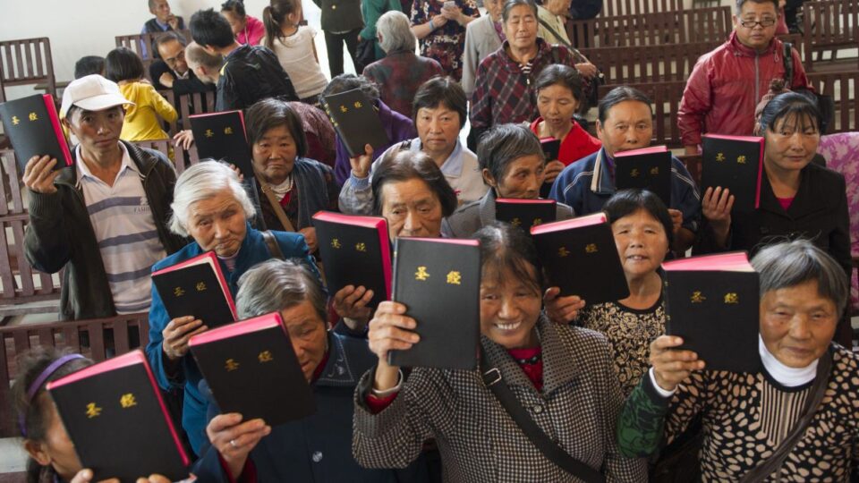 Eine Gruppe Menschen aus China, die voller Freude eine Bibel in die Höhe halten.