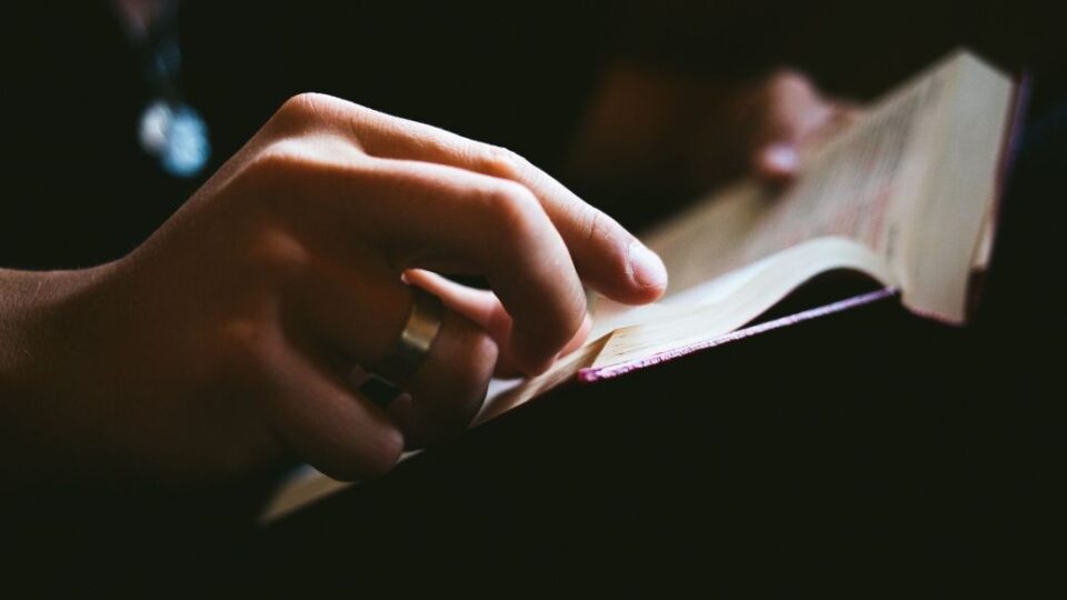 Aufgeschlagene Bibel mit einer Hand.